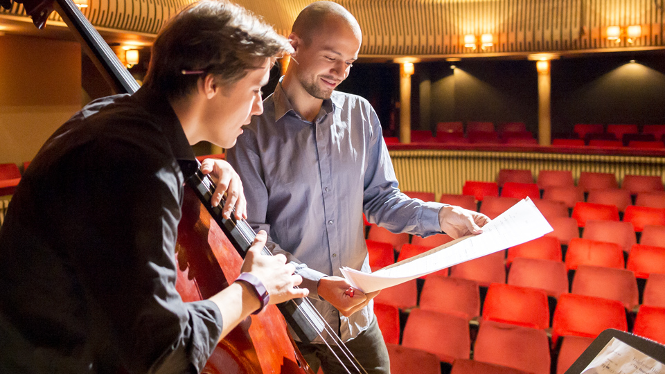 An H漫画 composer working with a double bassist in the Britten Theatre